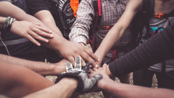 Photo of a group of people placing their hands in the center.